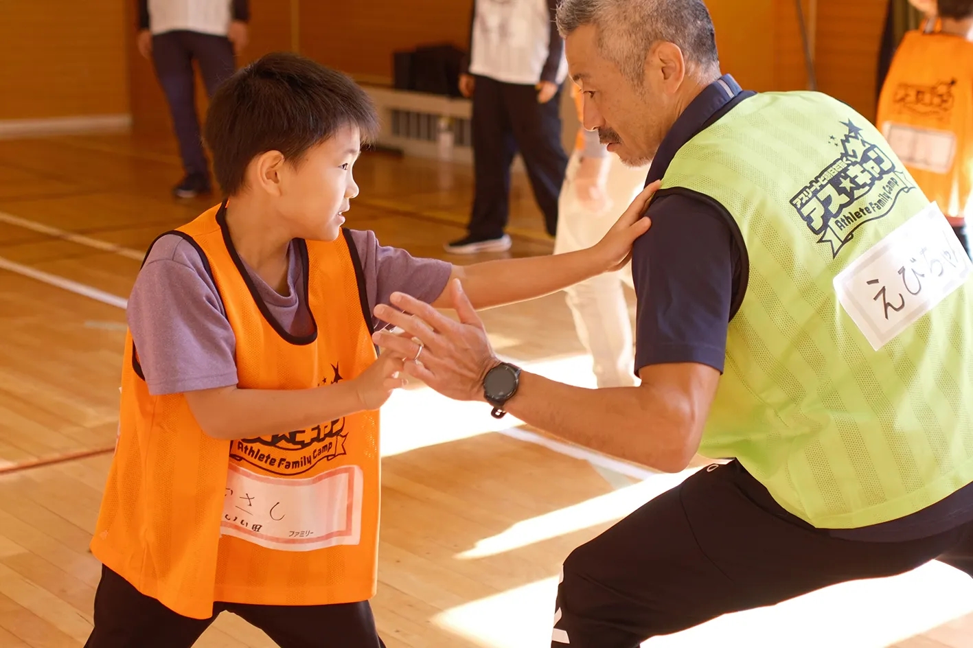子供たちとアスリートが自然の中で協力し合うイメージ